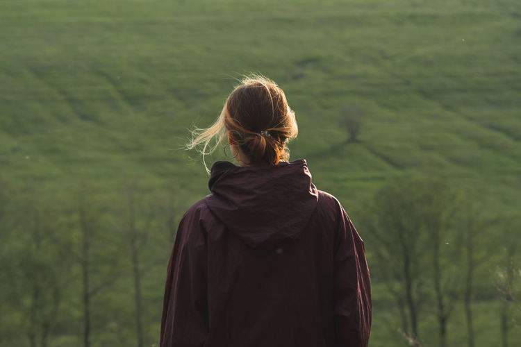 Back of a woman standing on the hills in windy weather. 