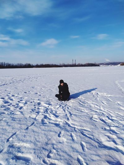 Man sitting on snow covered land