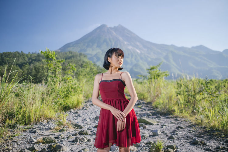 Full length of woman standing on rocks against mountain
