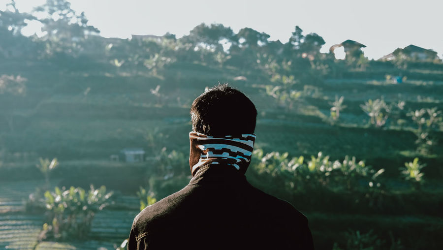 Rear view of man standing against plants