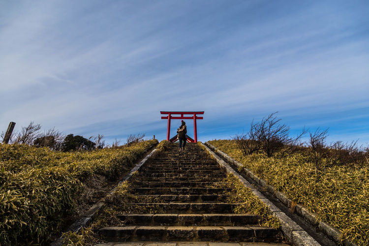Low angle view of woman on steps by torii gate