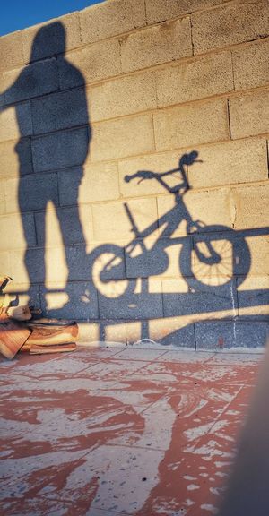 Shadow of person riding bicycle on footpath