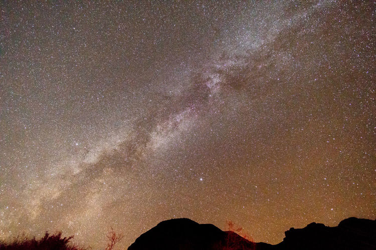 Low angle view of silhouette mountain against sky at night