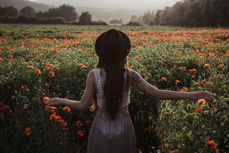 Rear view of woman standing amidst flowering plants