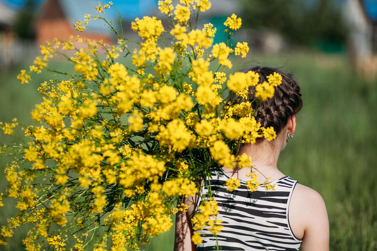 Low section of woman standing on yellow flowering plants