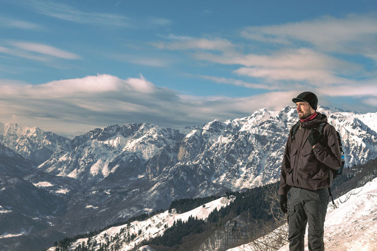 Man standing on mountain against sky during winter