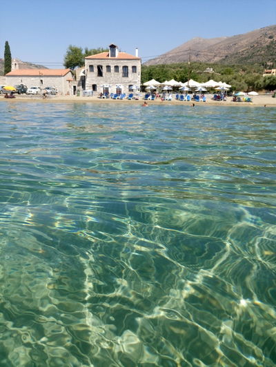 Sea by buildings against mountains