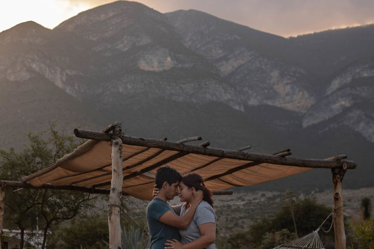 Couple kissing against mountains