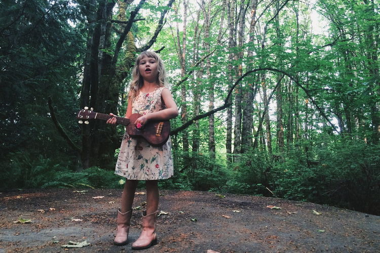 Portrait of girl playing ukelele in forest