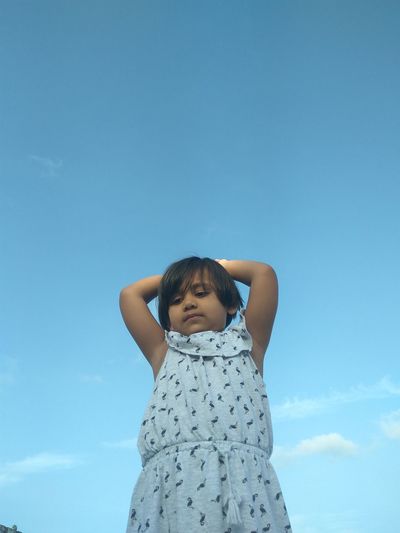 Low angle view of girl standing against clear sky