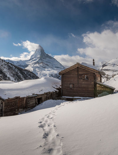 Snow covered houses and mountains against sky