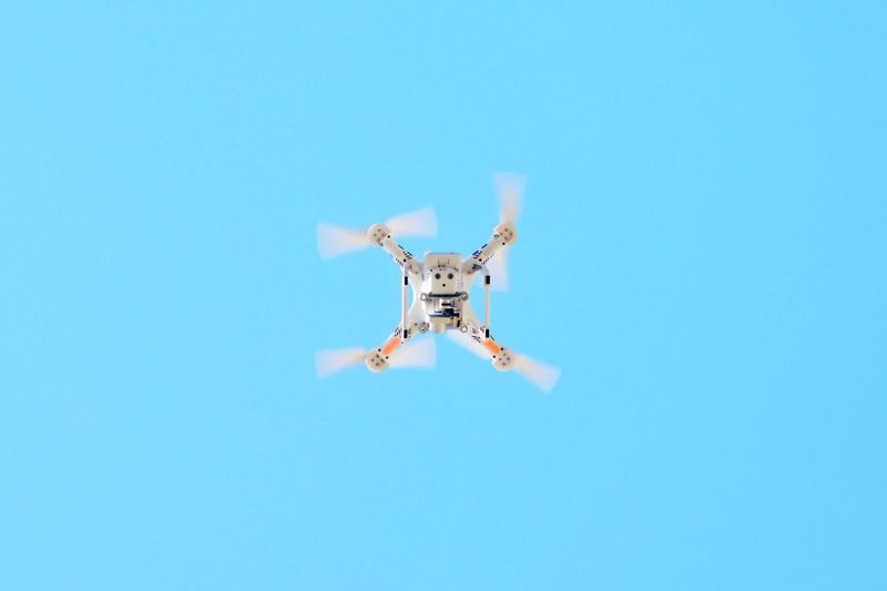 Low angle view of drone flying against clear blue sky