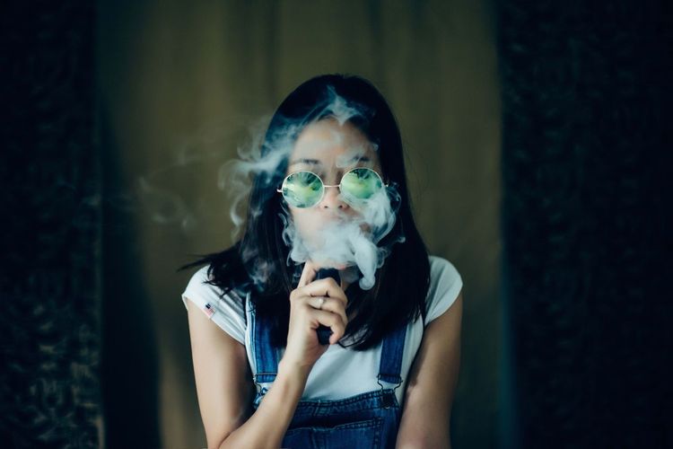 Woman smoking against curtains