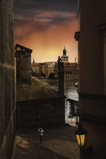 Street by buildings against sky during sunset