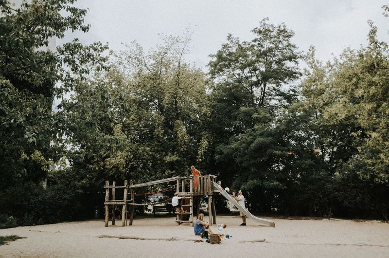 People playing on playground against trees