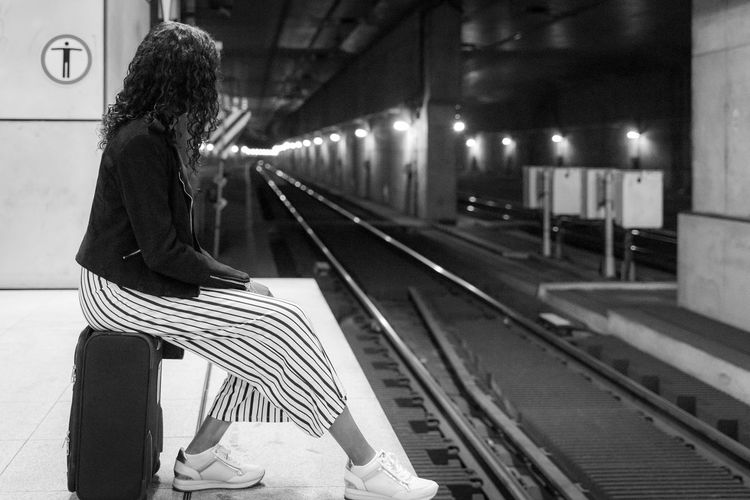 Woman sitting on railroad station platform