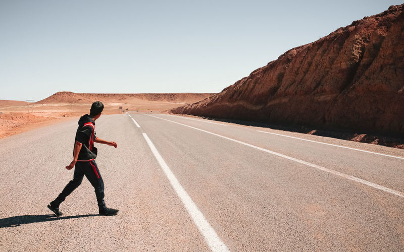 A man crossing the road, a highway in the desert of morocco.