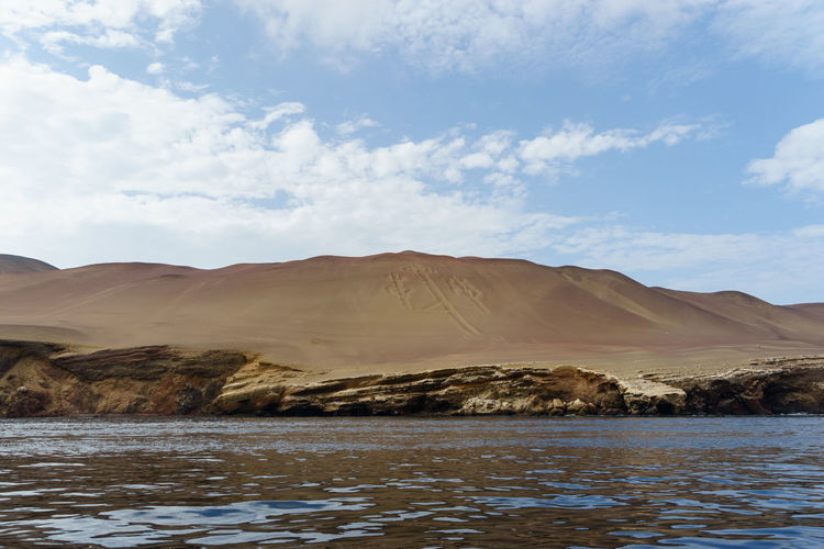 Idyllic view of sandy mountain and lake against sky at paracas