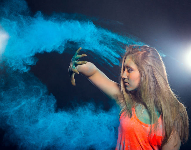 Close-up of woman with power paint standing against black background