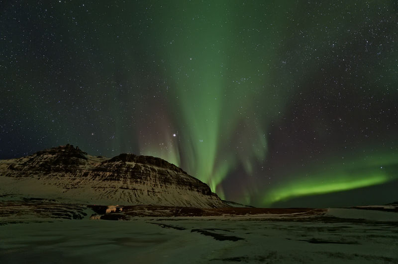 Low angle view of aurora borealis at night during winter