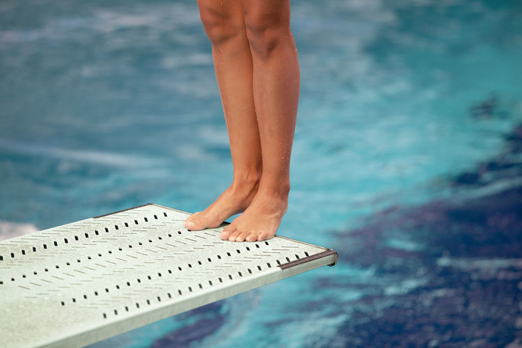 Low section of woman standing on diving board