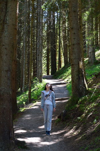 Woman standing on road amidst trees in forest