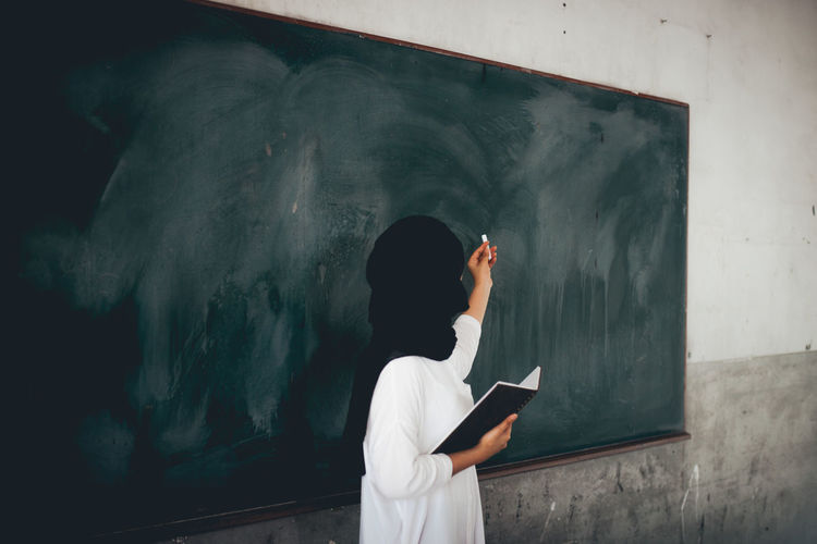 Adult Architecture Blackboard Board Communication Education Holding Indoors Leisure Activity Lifestyles Men One Person Real People Rear View Standing Waist Up Wall - Building Feature Writing
