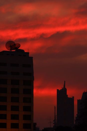 Silhouette of buildings against cloudy sky during sunset