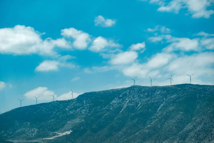 Wind turbines on mountain against sky