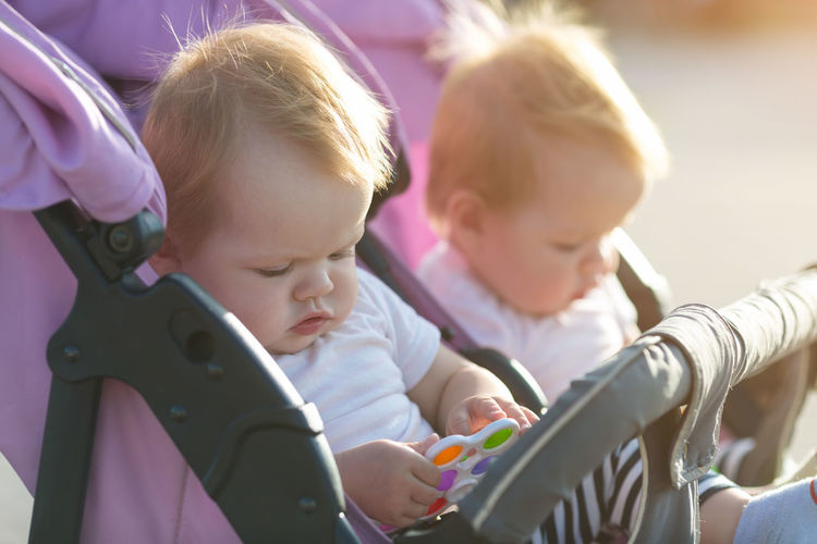 Close-up of cute girls sitting in baby stroller