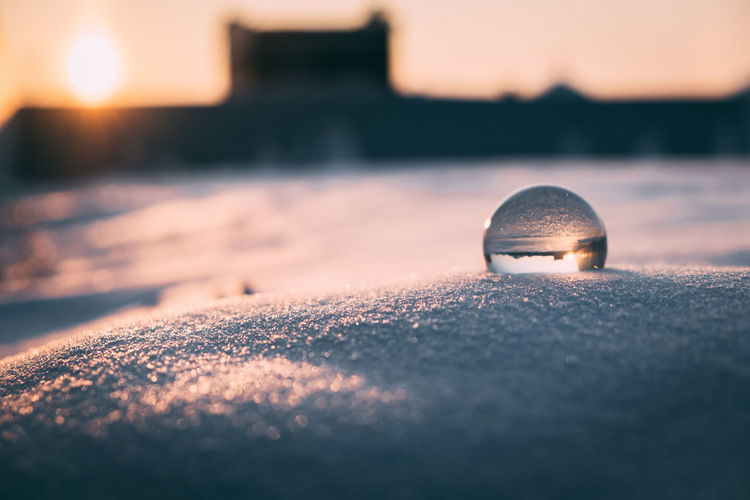 Glass transparent ball in the snow in winter, sun rays reflection. severe frost, cold