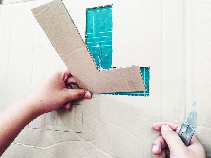 Cropped image of hands cutting cardboard