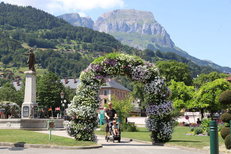 People on flowering plants against mountain