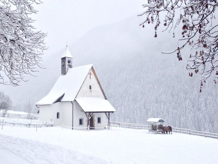 Church on snow covered field against tree mountain