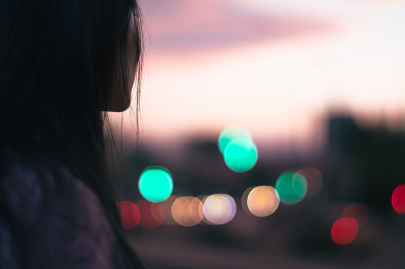 Rear view of asian woman on backround  of blurred city during sunset. close-up.