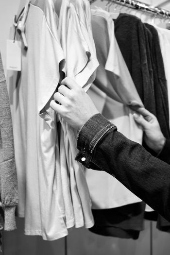 Cropped hand of woman choosing clothes at store