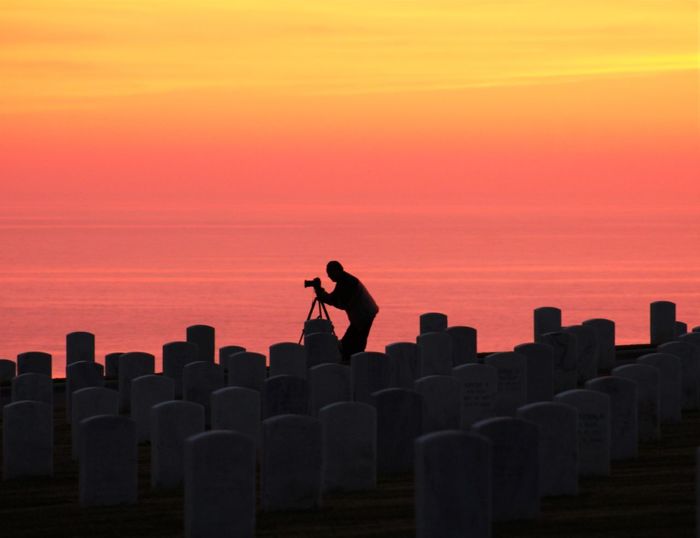 Silhouette man photographing by tombstones at fort rosecrans national cemetery