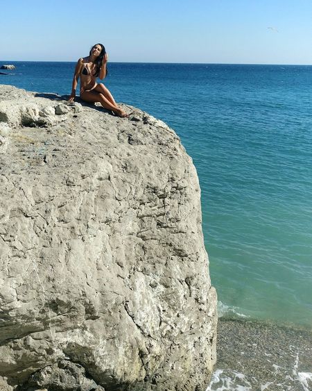 Young woman sitting on rock formation at beach