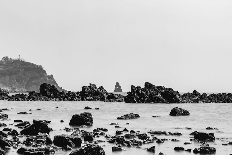 Rocks at seashore against clear sky