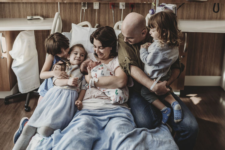Mid view of whole family holding newborn son in hospital