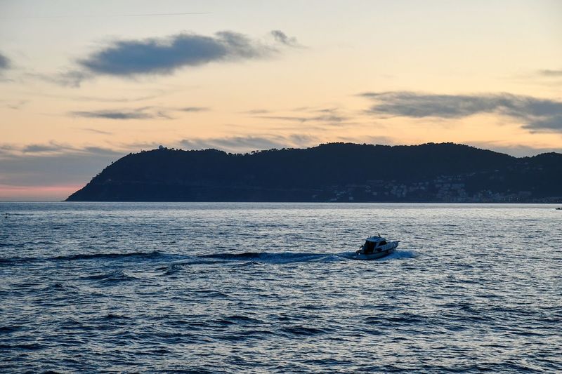 Boat sailing in sea against sky during sunset