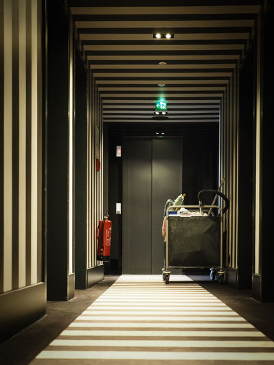 Cleaning cart and fire extinguisher in illuminated hotel corridor