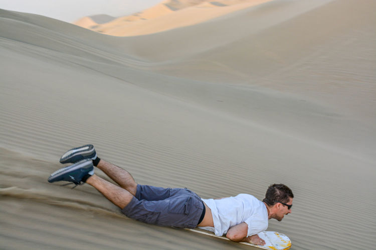 Full length of man sandboarding in desert