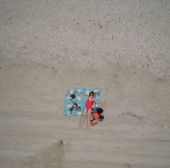 Aerial view of woman relaxing on shore at beach
