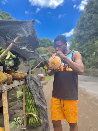 Rear view of man holding fruits at beach