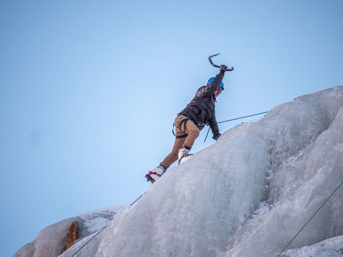 Low angle view of man with arms raised on snow against sky