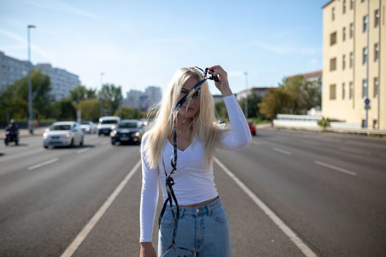 Portrait of woman holding ribbon standing on road against sky