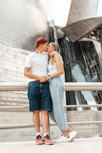 Young couple kissing while standing in front of building
