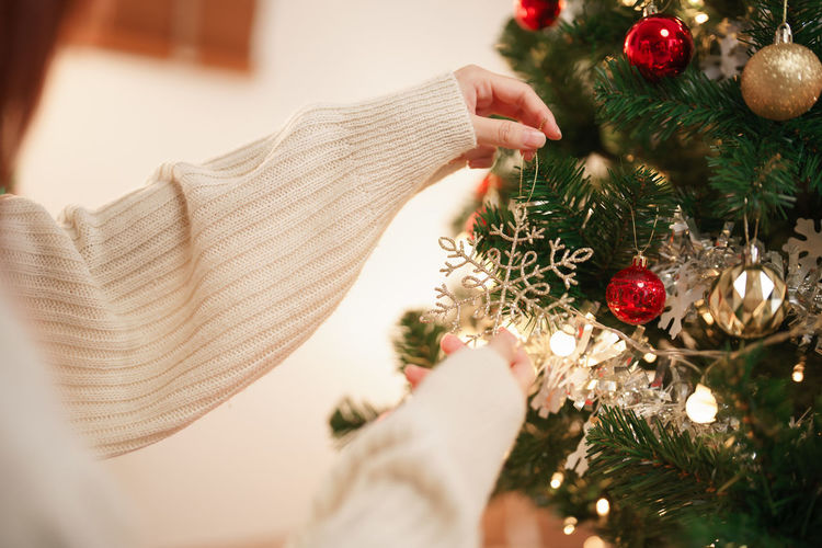 Cropped hand of woman decorating christmas tree