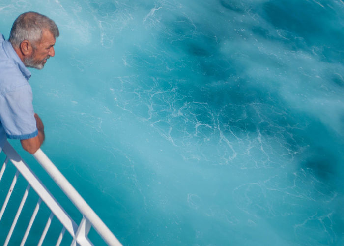 High angle view of man standing by railing while looking at sea